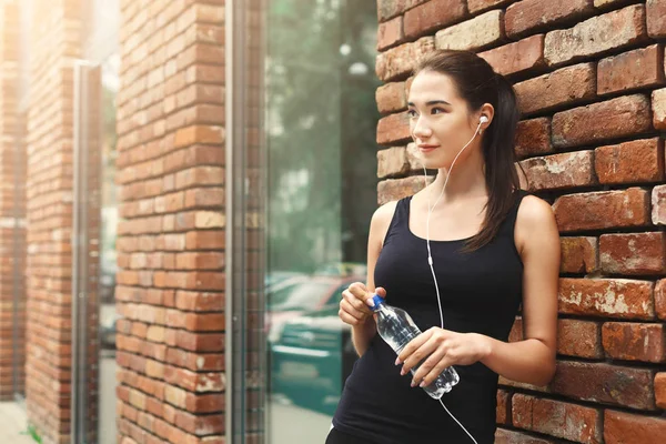 Vrouw runner heeft pauze, drinkwater — Stockfoto