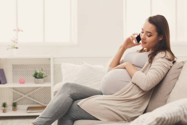 Gülümseyen hamile kadın onun smartphone üzerinde söz