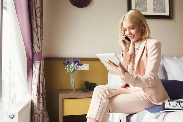 Retrato de empresária sentada na cama e usando tablet — Fotografia de Stock