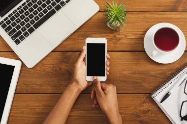 Ahşap ofis masaüstü, üstten görünüm Smartphone tutarak siyah eller