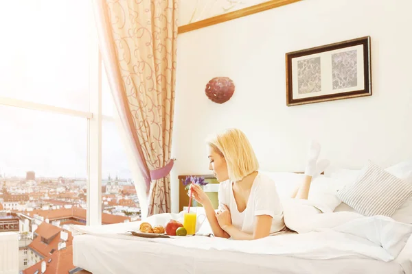 Mulher bonita deitada na cama e tomando café da manhã — Fotografia de Stock