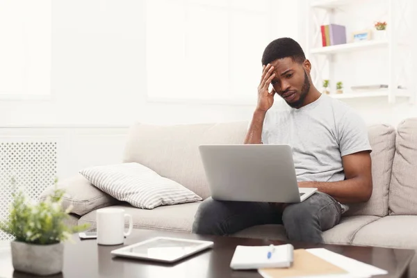 Giovane uomo sconvolto a casa messaggistica online sul computer portatile — Foto Stock