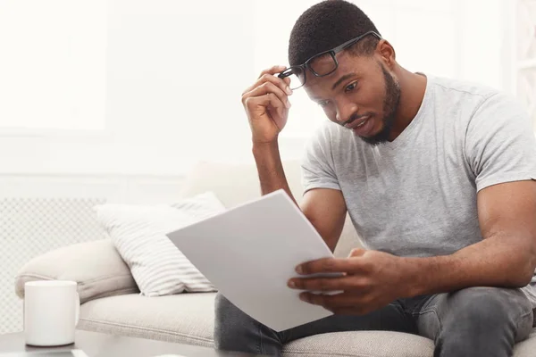 Sonriente joven empresario leyendo papeleo en casa —  Fotos de Stock