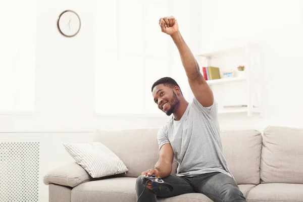 Счастливый молодой человек дома играет в видеоигры и выигрывает — стоковое фото