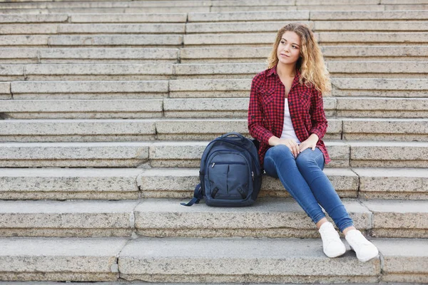 Açık havada merdivenlerde oturan kız öğrenci