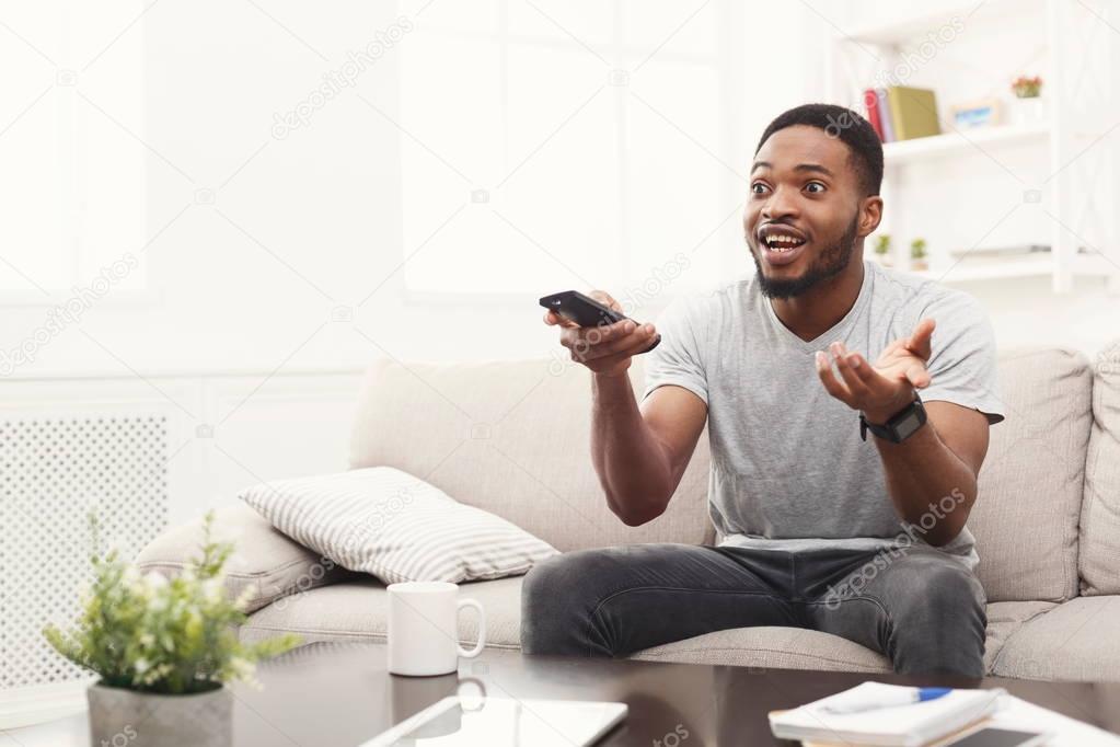 Emotional young man watching tv at home