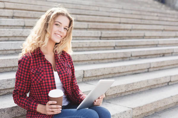 Kvinnlig student arbetar på en bärbar dator och dricka kaffe utanför — Stockfoto