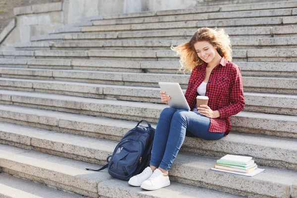 Studentka pracuje na tabletu a pití kávy mimo — Stock fotografie