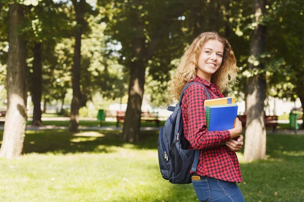 Счастливая студентка стоит в парке — стоковое фото