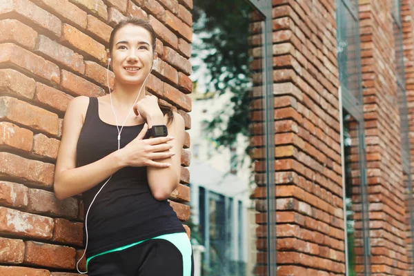 Mujer joven usando reloj inteligente, ladrillo backgroud — Foto de Stock