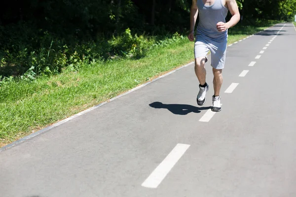 Joven trotando en la cinta de correr en el parque, espacio de copia —  Fotos de Stock