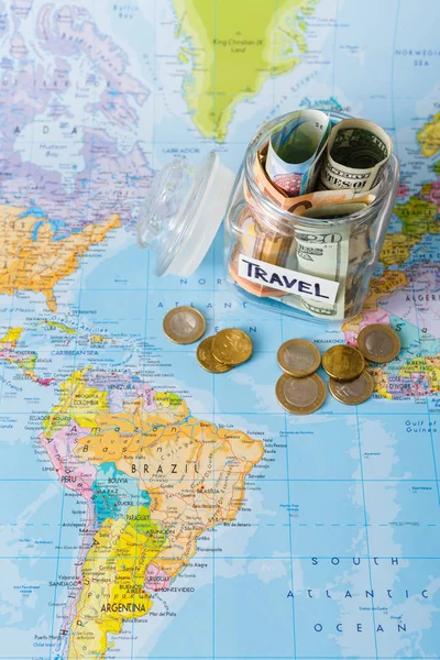 Travel budget concept. Money saved for vacation in glass jar on map