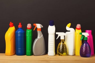 Group of colorful cleaning products on dark background clipart