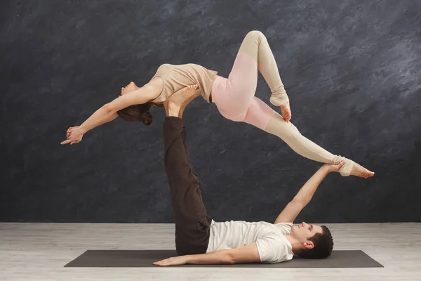 若いカップルが一緒にマットで acroyoga の練習 — ストック写真