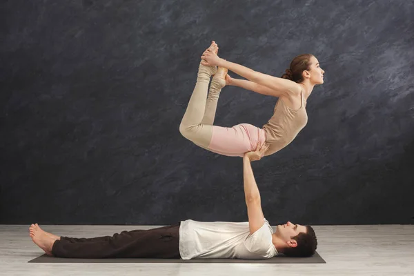 若いカップルが一緒にマットで acroyoga の練習 — ストック写真