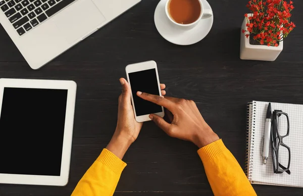 Negro manos femeninas sosteniendo el teléfono inteligente, vista superior — Foto de Stock