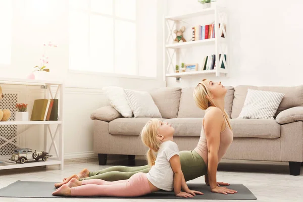 Madre e hija haciendo ejercicios de yoga en casa —  Fotos de Stock