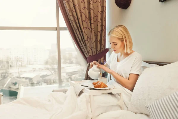 아름 다운 젊은 여 자가 침대에 앉아서 아침 식사 — 스톡 사진