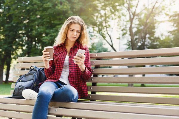 Hermosa mujer sentada y usando teléfono inteligente al aire libre — Foto de Stock