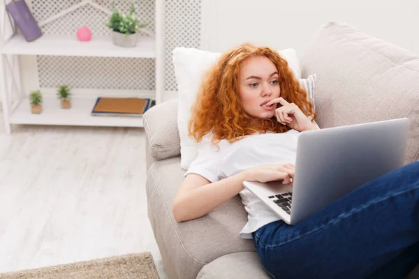 Evde serbest zaman. Kanepe üstünde laptop dalgın kızla — Stok fotoğraf