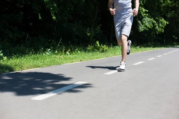 Junger Mann joggt auf Laufband im Park — Stockfoto