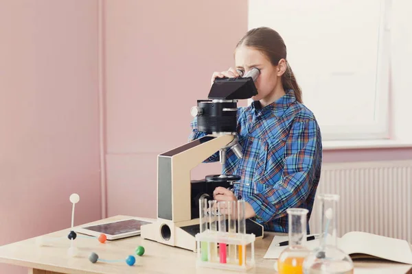 Školačka v mikroskopu při pohledu na lekci — Stock fotografie