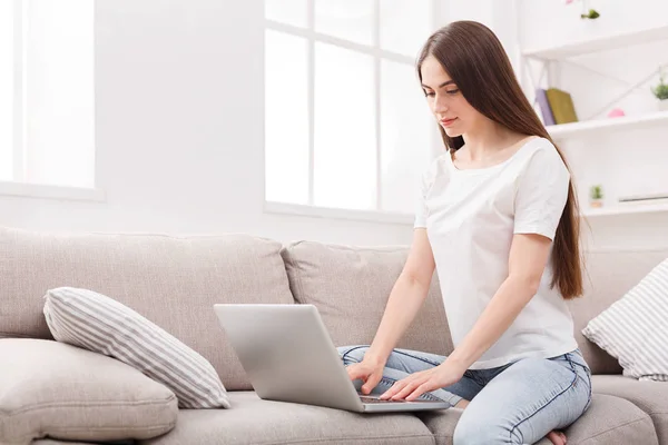 Ragazza con computer portatile sul divano — Foto Stock