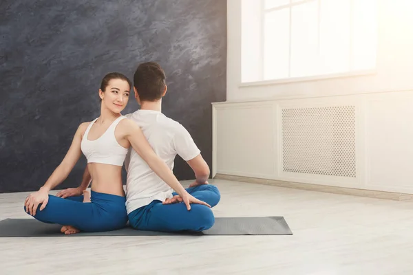 Pareja joven practicando yoga juntos en estudio —  Fotos de Stock