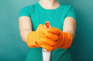 Woman in gloves holding spray of cleaning fluid clipart