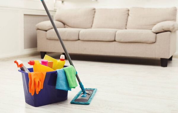 Bucket with sponges, chemicals bottles and mopping stick.