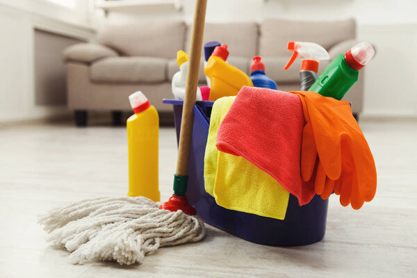Bucket with sponges, chemicals bottles and mopping stick.