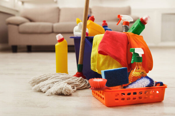 Bucket with sponges, chemicals bottles and mopping stick.
