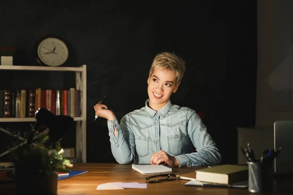 Lächelnde Frau, die bis spät abends im Büro arbeitet — Stockfoto