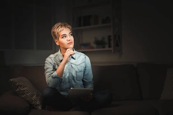 Femme réfléchie avec tablette au bureau à la maison sombre, espace de copie — Photo