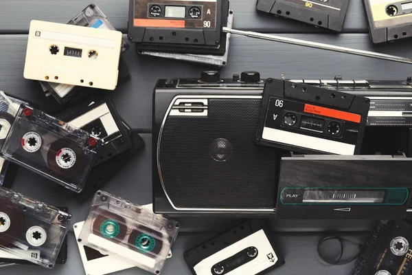 Heap of vintage audio cassettes and tape recorder at gray background