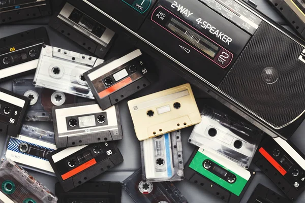 Heap de cassetes de áudio vintage e gravador de fita em fundo cinza — Fotografia de Stock