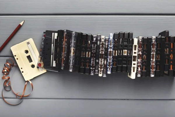 Винтажные кассеты и карандаш для перемотки ленты на сером деревянном фоне — стоковое фото
