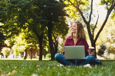 Bir dizüstü bilgisayar açık havada kullanan güzel genç kadın