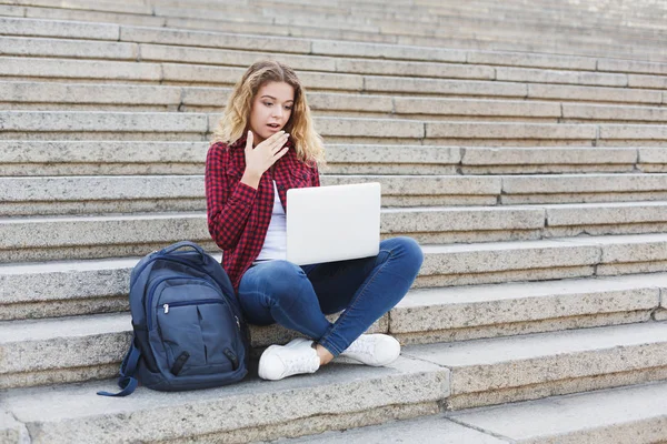 Kvinnlig student sitter på trappan och arbetar med bärbara utomhus — Stockfoto