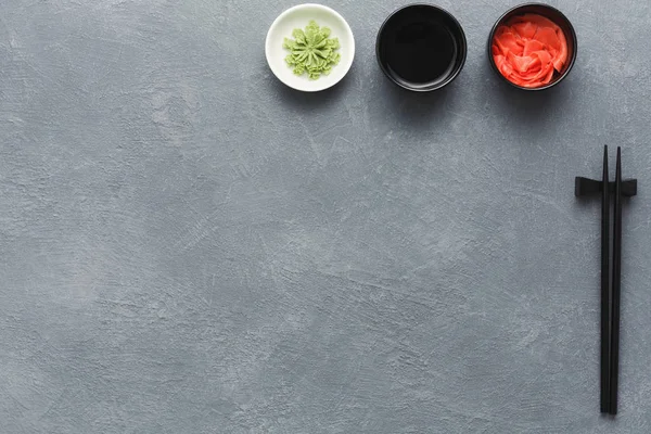 Bovenaanzicht op stokjes, gember, wasabi en soja — Stockfoto