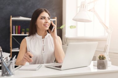 Dizüstü bilgisayarda çalışan ve telefonla danışmanlık genç kadın