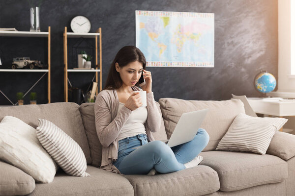 Woman with a laptop, talking on mobile and drinking coffee