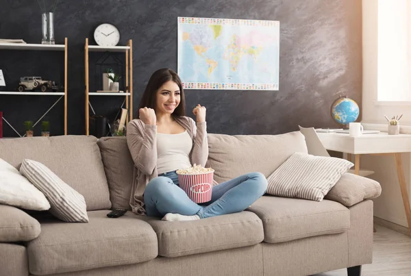 Young woman sitting on the couch and watching tv — Stock Photo, Image