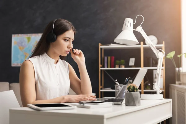 Serio joven operador de servicio al cliente chica que trabaja en el ordenador portátil — Foto de Stock