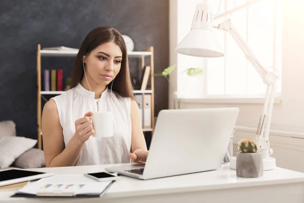 Mujer joven que trabaja en el ordenador portátil y la consulta en el teléfono — Foto de Stock