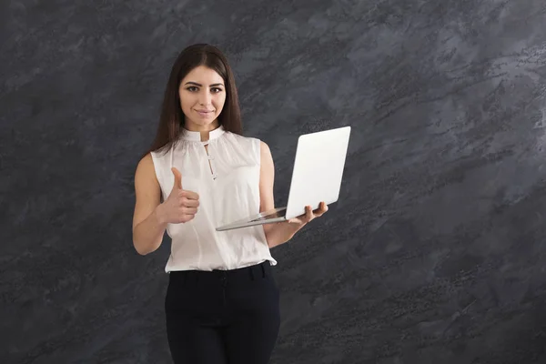 Šťastná žena s laptopem na šedém pozadí — Stock fotografie
