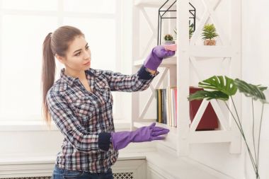 Kitaplıktaki tozları temizleyen kadın