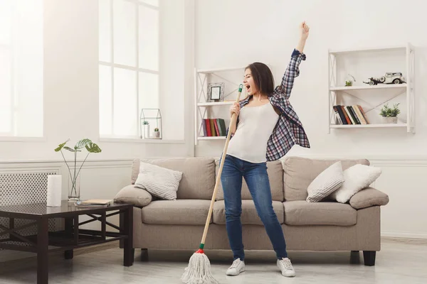 Šťastná žena čištění domů s mopem a baví — Stock fotografie