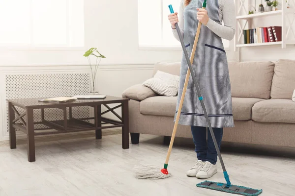 Неузнаваемая женщина убирает дом шваброй — стоковое фото