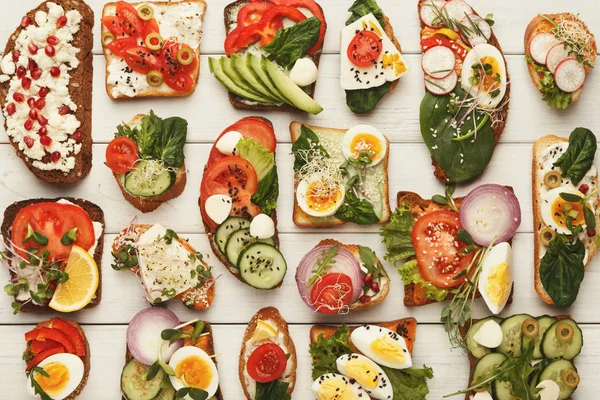 Variety of healthy vegetarian sandwiches on white wood, top view — Stock Photo, Image